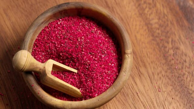 Sumac spice powder in bowl with scoop rotation