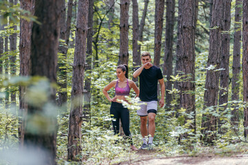 Fototapeta premium Fit couple taking a rest after fast running workout in the woods