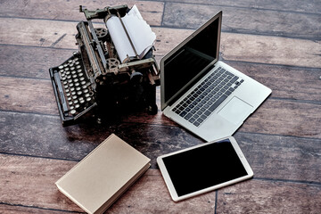 From above of retro typewriter placed on table with agenda and modern netbook and tablet