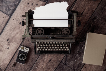 From above of old fashioned typewriter with paper placed on table with retro photo camera and notebook