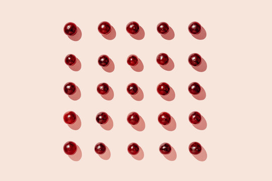 Top view of pattern of fresh red grapes arranged in lines on pink surface in studio