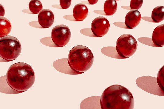 From above pattern of fresh red grapes arranged in lines on pink surface in studio