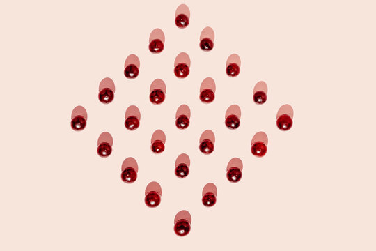 Top view of pattern of fresh red grapes arranged in lines forming a square shape on pink surface in studio