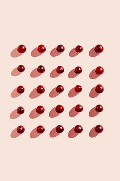 Top view of pattern of fresh red grapes arranged in lines on pink surface in studio