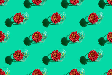 Seamless pattern of a glass with water and deep red flower Dahlia on green background. Minimal flowers concept in hard light with shadows. Art design. Top view, soft focus.