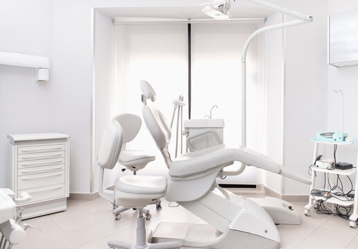 Leather dental chair with various medical instruments located in white dentist office