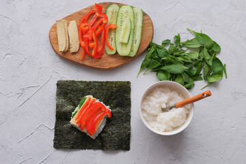 The process of making onigirazu, vegan sushi sandwich with vegetables (cucumber, pepper, spinach) and tofu. Trend Japanese food. Healthy food concept.