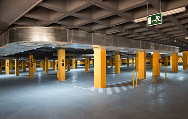 Modern parking lot with yellow stone columns and concrete floor located underground