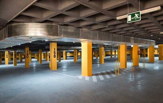 Modern parking lot with yellow stone columns and concrete floor located underground