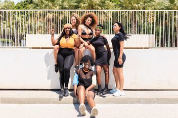 Group of young multiracial female friends gathering on sidewalk and looking at camera