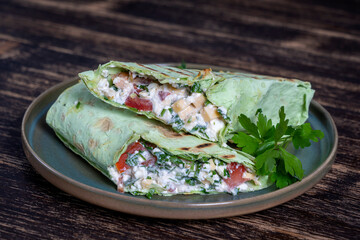 Green vegan burrito. Sliced up raw food wrap with vegan ingredients on a plate
