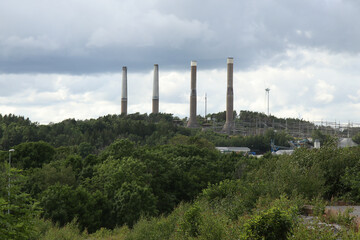 Obraz premium Chimneys of a power plant on a wooded hill in western Sweden