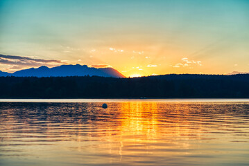 Beeindruckender Sonnenuntergang hinter Berg und See.