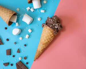 Chocolate ice cream in a waffle cone on a pink and blue background with marshmallows and chocolate. Pop art style.