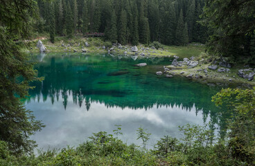 Lake Carezza,  a small green mountain lake at the foot of Latemar mountain, near Nova Levante, in a cloudy and rainy late afternoon, Dolomites, South Tirol, Alto-Adige, Trentino, Italy.