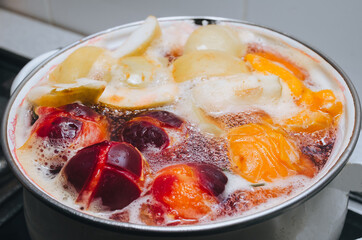 Fruit compote: apricots, plums, apples, cherries are cooked in a metal pan in boiled water with bubbles. Making juice on the stove.