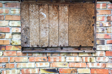 Boarded up window in abandoned old brick wall in barn or closed old house. Close-up.