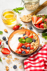 Greek yogurt granola with fresh berries on white stone table.