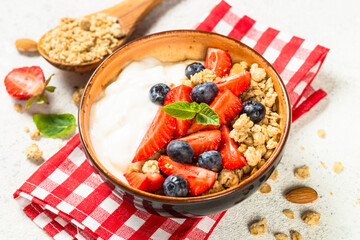 Greek yogurt granola with fresh berries on white stone table.
