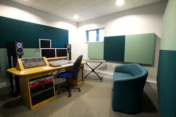 Sound studio with speakers, monitors, a sound board and sound absorbers on the walls,