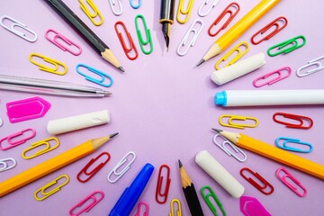 Stationery on a pink background form a circle.