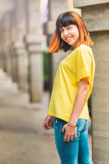 Fototapeta premium Alternative caucasian model with orange hair looking back smiling on a city background.