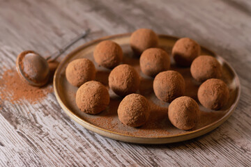 Energy balls in sugar free cocoa. Vegetarian sweets. Round delicious dessert on a ceramic plate. Healthy natural products for people. Handmade.
