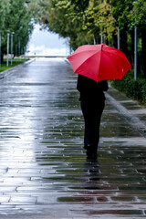 Woman with red umbrella walking on wet road