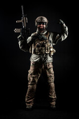 USA soldier in a military suit with a rifle smiles and shows strength against a dark background,...