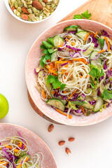 Vegetarian food. Salad with noodles, vegetables and sesame seeds in a bowl on a white served table top view. Delicious and healthy food.