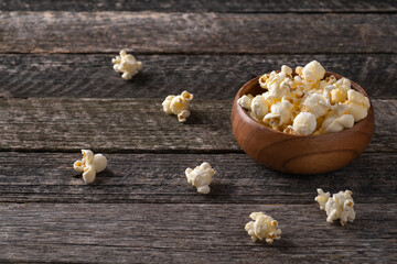 Popcorn in a wooden bowl in rustic style.  Wooden bowl with fresh popcorn
