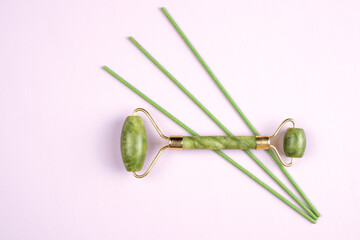 Jade face massager isolated on textured background. Gua Sha massager for face. Beauty skin care. 