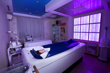 Young happy girl enjoys the procedure of wrapping and hydro massage in the Spa salon. Professional...