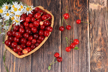 Fresh berries of cherries in a basket on a light table, top view, sweet cherry on a wooden light background, selective focus. Natural food concept, healthy breakfast, harvesting