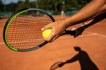shadow of a tennis player on an outdoor clay tennis court performing a serve