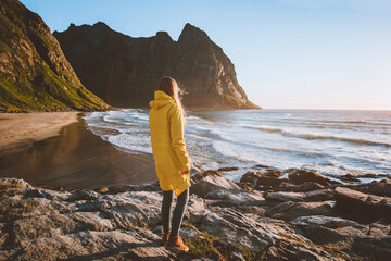 Woman in yellow raincoat walking alone on Kvalvika beach in Norway enjoying ocean view travel lifestyle vacation trip outdoor © EVERST