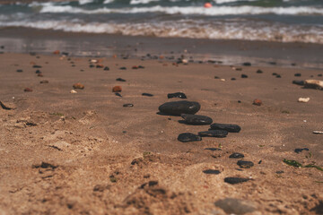 Black flat zen stones lie on the sand of a sea beach