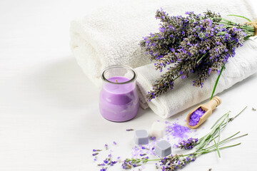 Lavender flowers, products and white towels on the white background. Bath aromatherapy, health care concept.