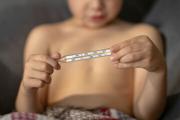 A close-up glass thermometer shows a temperature of thirty-nine degrees. Child's hands hold a thermometer