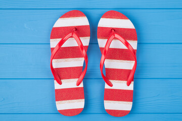 Top above overhead view close-up photo of a pair of red and white striped flipflops in center isolated on blue wooden background