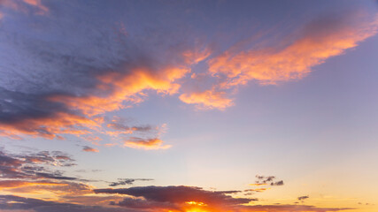 Idyllic and dramatic sunset sky with motion clouds in the English Warwickshire countryside. Purple, orange and golden tones. Background design asset.