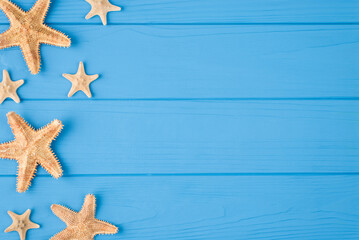 Fototapeta na wymiar Top above overhead view close-up photo of starfish placed to the left side isolated on blue wooden background with copyspace