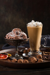 A glass of coffee latte, chocolate ice cream and truffles on a dark background.
