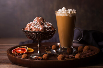 A glass of coffee latte, chocolate ice cream and truffles on a dark background.
