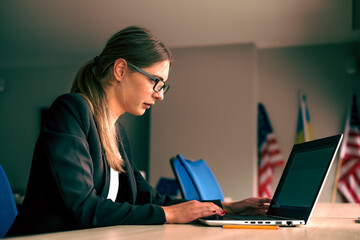 Business girl in glasses with a laptop sitting in front of the window. Development of women's business