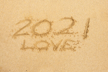 Hand written sign on a yellow warm sand 2021 and love.