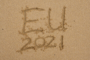 Hand written sign on a yellow warm sand  EU and 2021