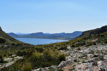 mountain landscape with light blue sea, blue sky and clouds