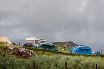 Tent, motor home and trailer site in a field. Cloudy sky. West of Ireland, Concept summer travel and outdoor activity.