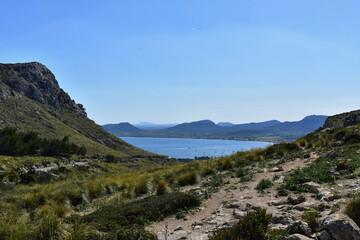 mountain landscape with light blue sea, blue sky and clouds